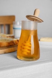 Photo of Jar of tasty honey, milk and bread with butter on white table