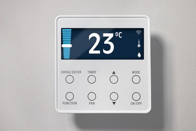 Image of Thermostat displaying temperature in Celsius scale and different icons. Smart home device on light wall