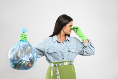 Photo of Woman holding full garbage bag on light background