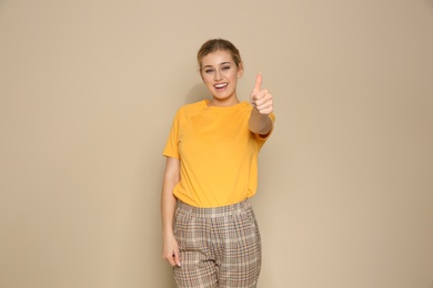 Photo of Happy young woman showing thumb up gesture on color background. Celebrating victory