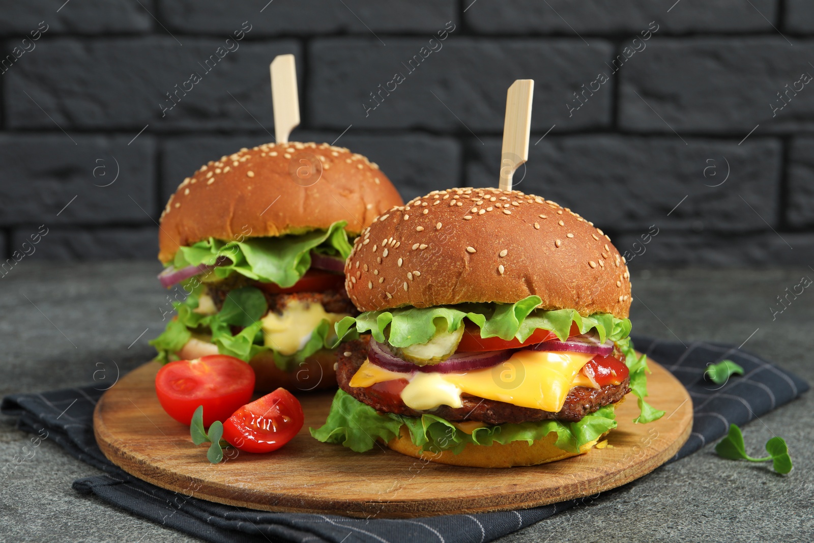 Photo of Delicious burgers with beef patty and tomatoes on grey table