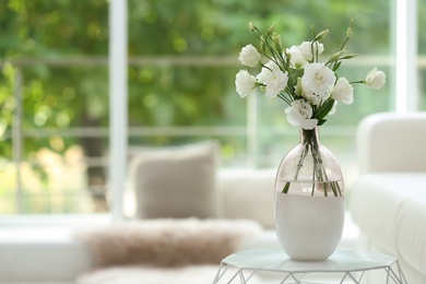 Photo of Vase with fresh flowers on white table in living room. Space for text