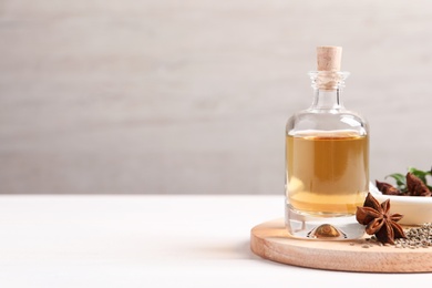 Photo of Anise essential oil and spice on white table, space for text