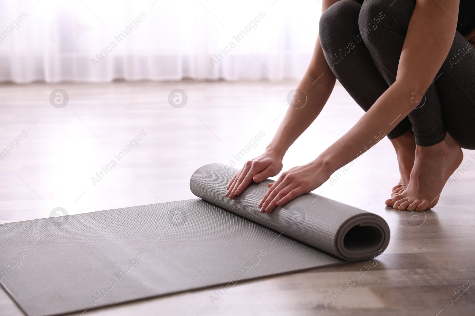 Photo of Woman rolling yoga mat in studio, closeup