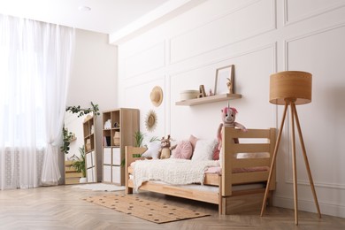 Photo of Cute child's room interior with comfortable bed and toys