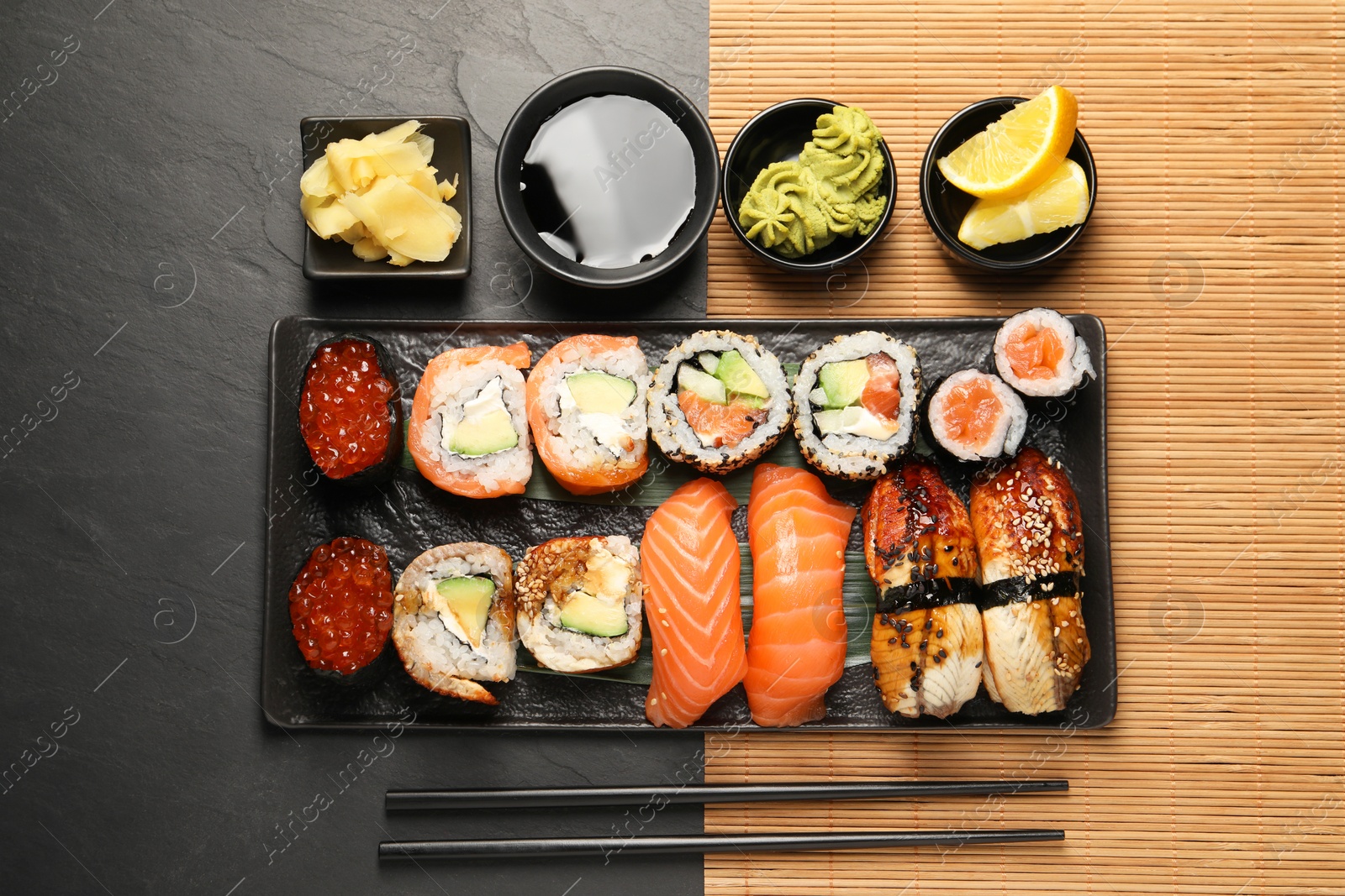 Photo of Set of delicious sushi rolls on black table, flat lay