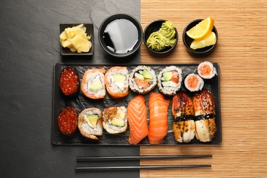 Set of delicious sushi rolls on black table, flat lay