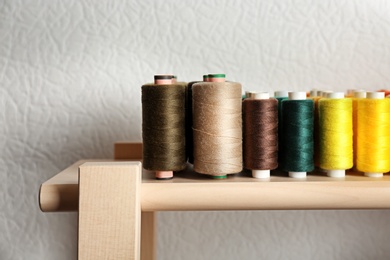 Photo of Set of color sewing threads on wooden shelf