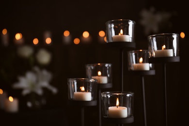 Burning candles on blurred background, space for text. Funeral symbol