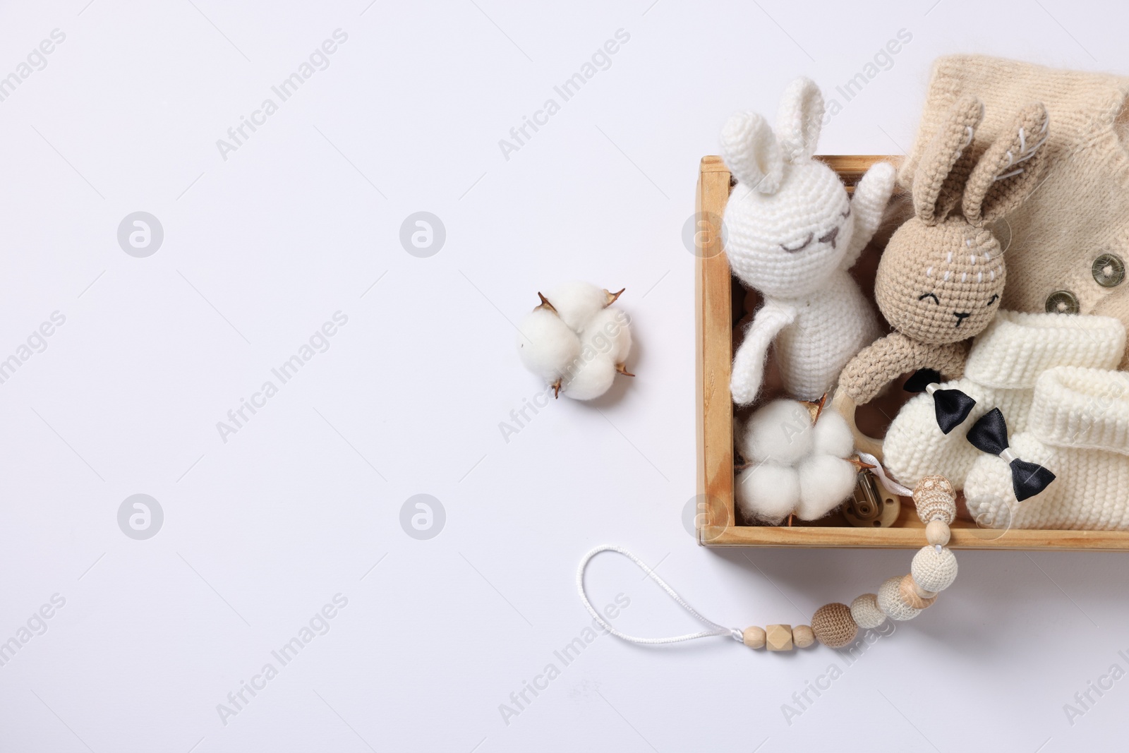 Photo of Different baby accessories and clothes in wooden crate on white background, top view. Space for text