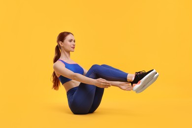 Young woman in sportswear doing exercises on yellow background