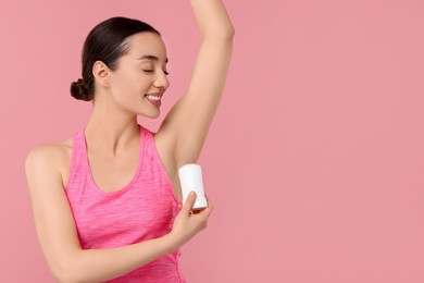 Photo of Beautiful woman applying deodorant on pink background, space for text