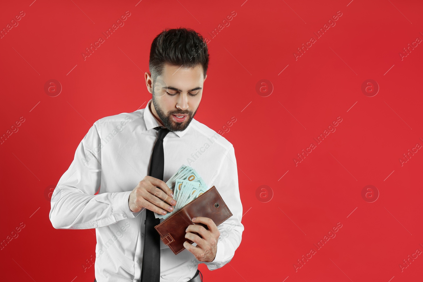 Photo of Young man with money and wallet on crimson background. Space for text