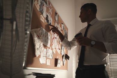 Detective looking at evidence board in office