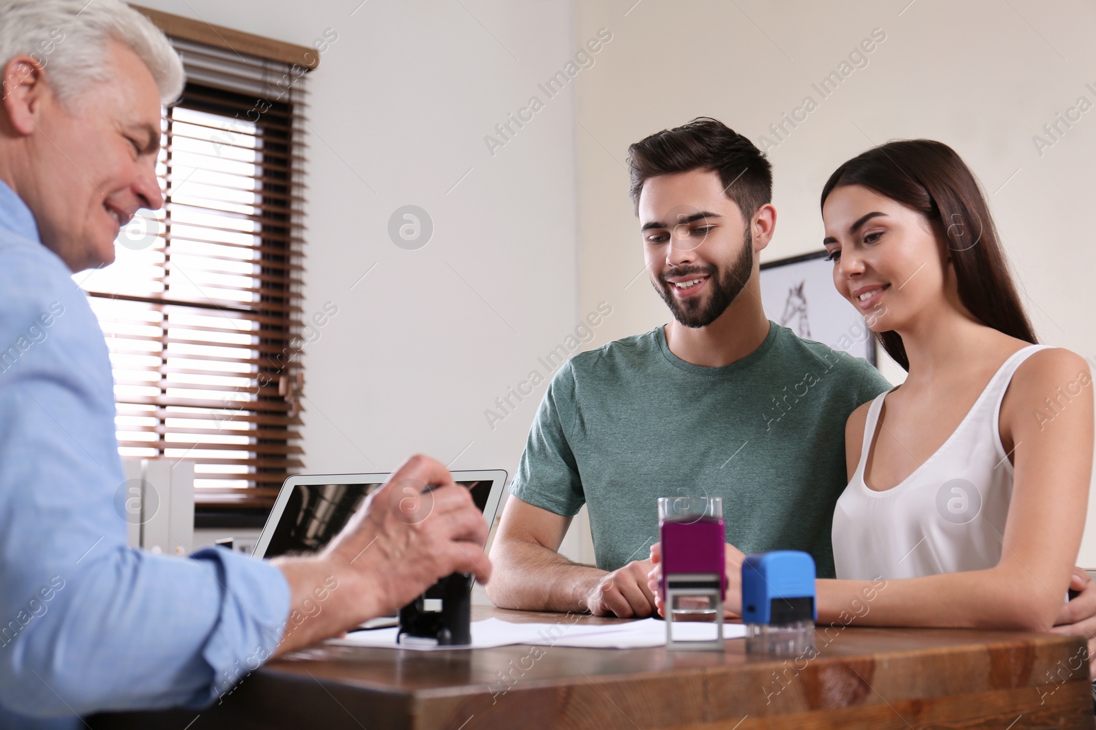 Photo of Senior notary working with young couple in office