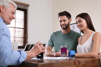 Photo of Senior notary working with young couple in office