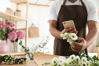 Florist taking picture of beautiful flowers in workshop, closeup