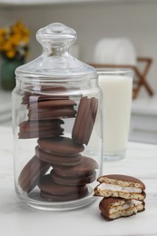 Jar with delicious choco pies and glass of milk on white table in kitchen