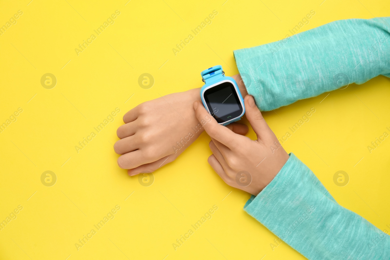 Photo of Boy with stylish smart watch on yellow background, top view
