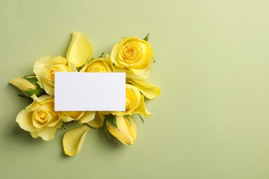 Photo of Beautiful yellow roses, petals and blank card on light olive background, flat lay. Space for text