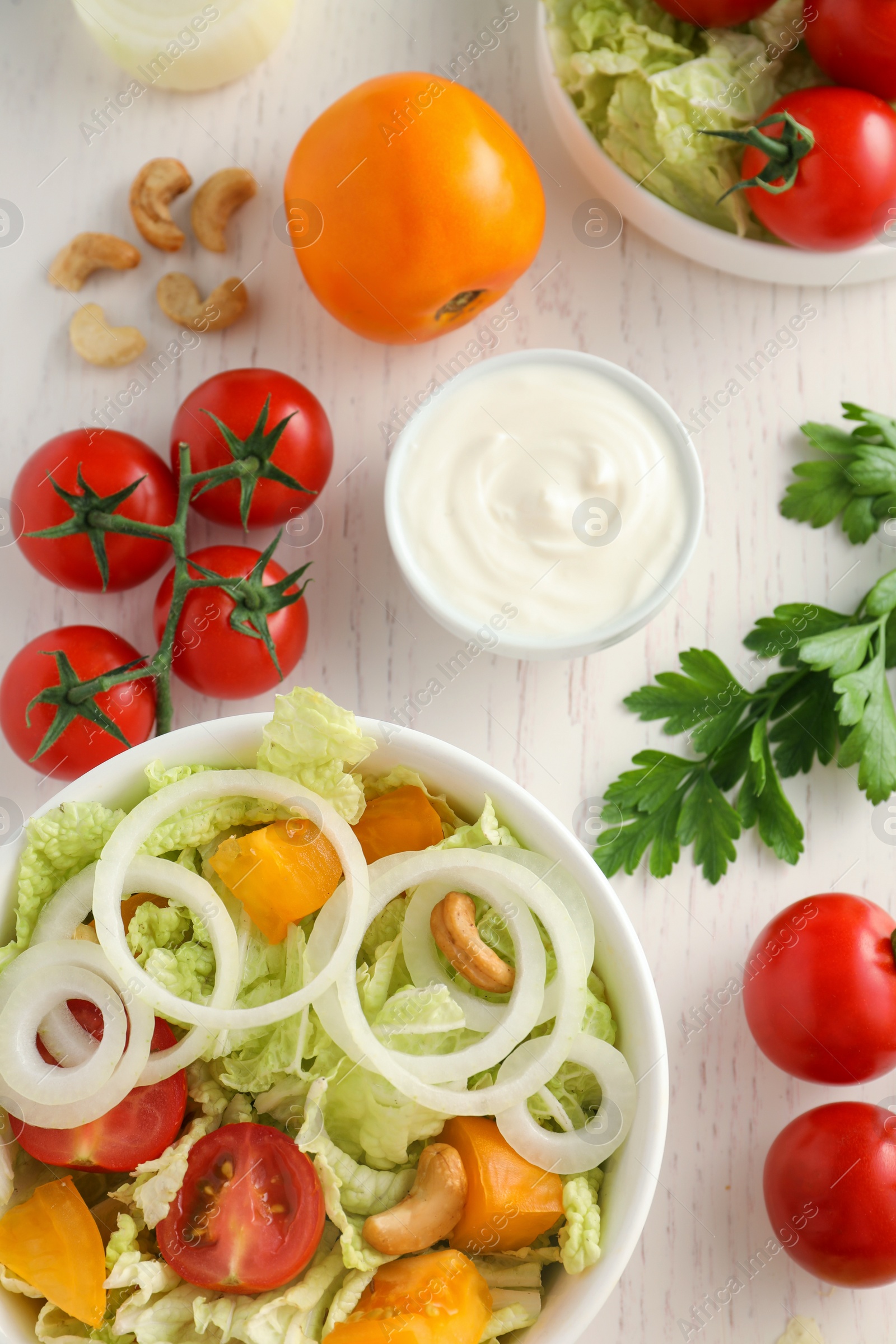 Photo of Bowl of delicious salad with Chinese cabbage and different ingredients on white wooden table, flat lay