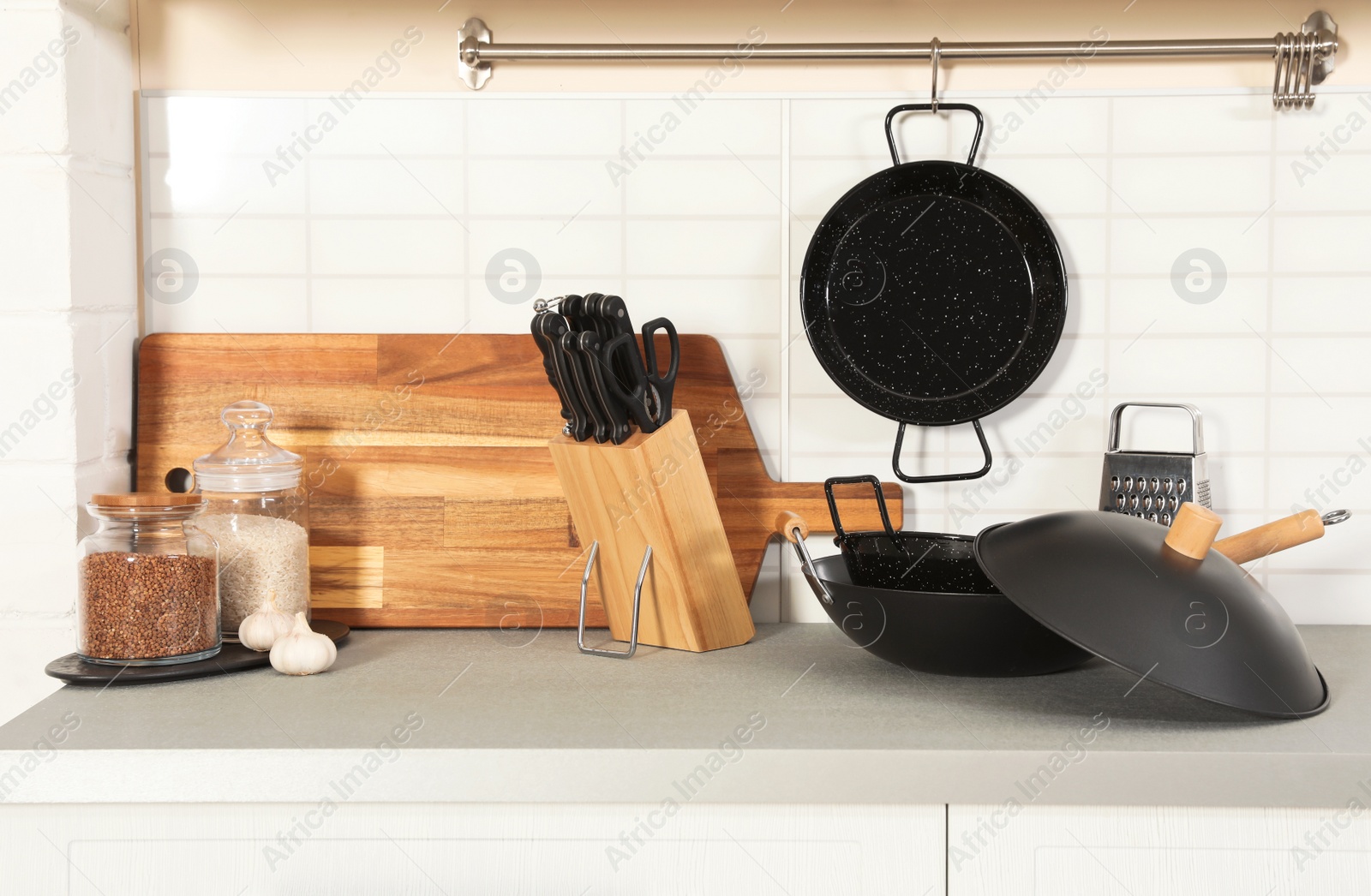 Photo of Set of clean cookware, utensils and products on table in modern kitchen