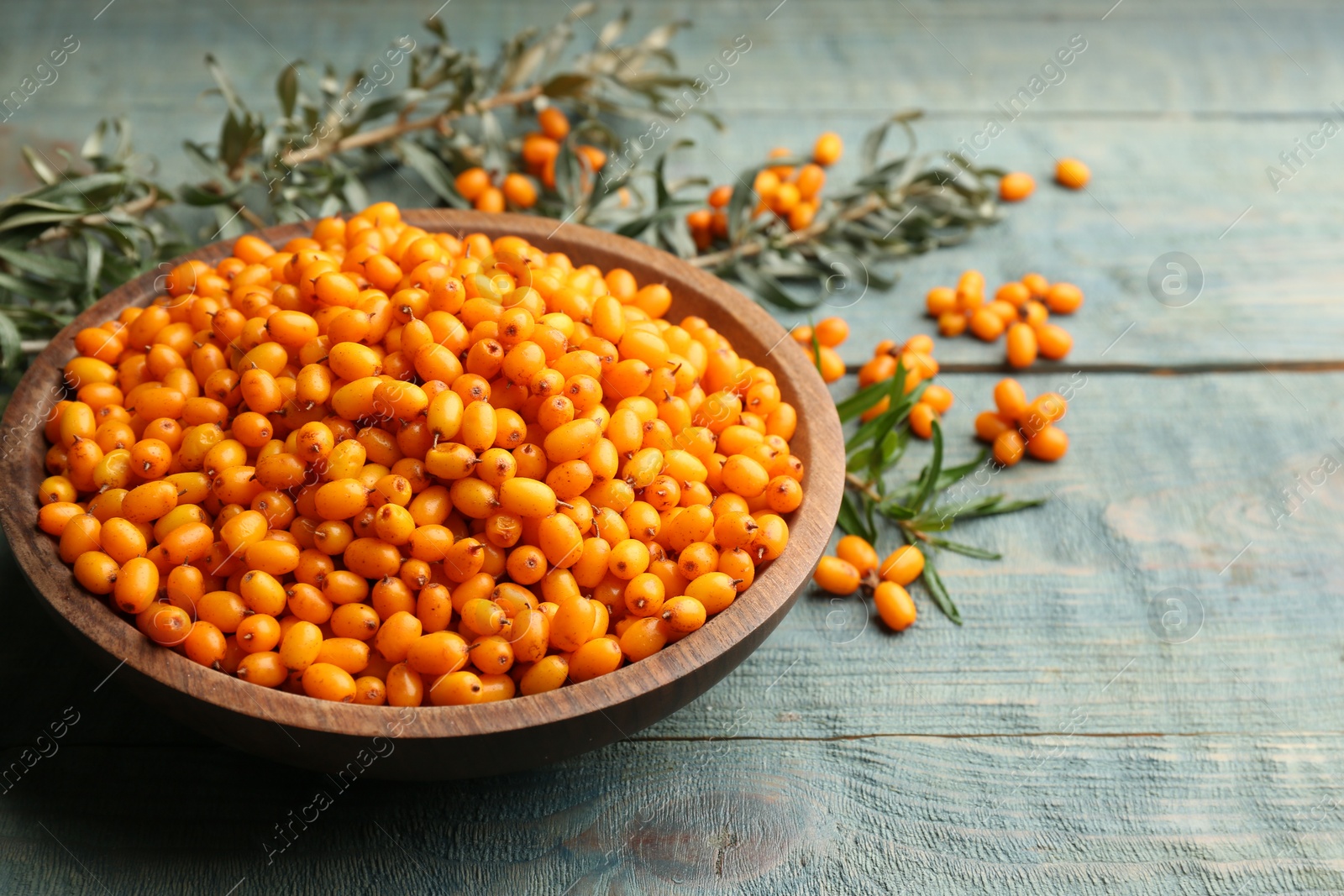 Photo of Ripe sea buckthorn berries on blue wooden table