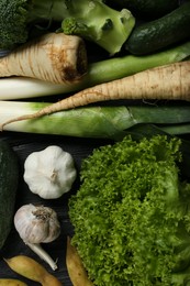 Photo of Different fresh ripe vegetables on black wooden table, flat lay. Farmer produce