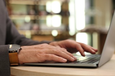 Photo of Man working on laptop at table in cafe, closeup