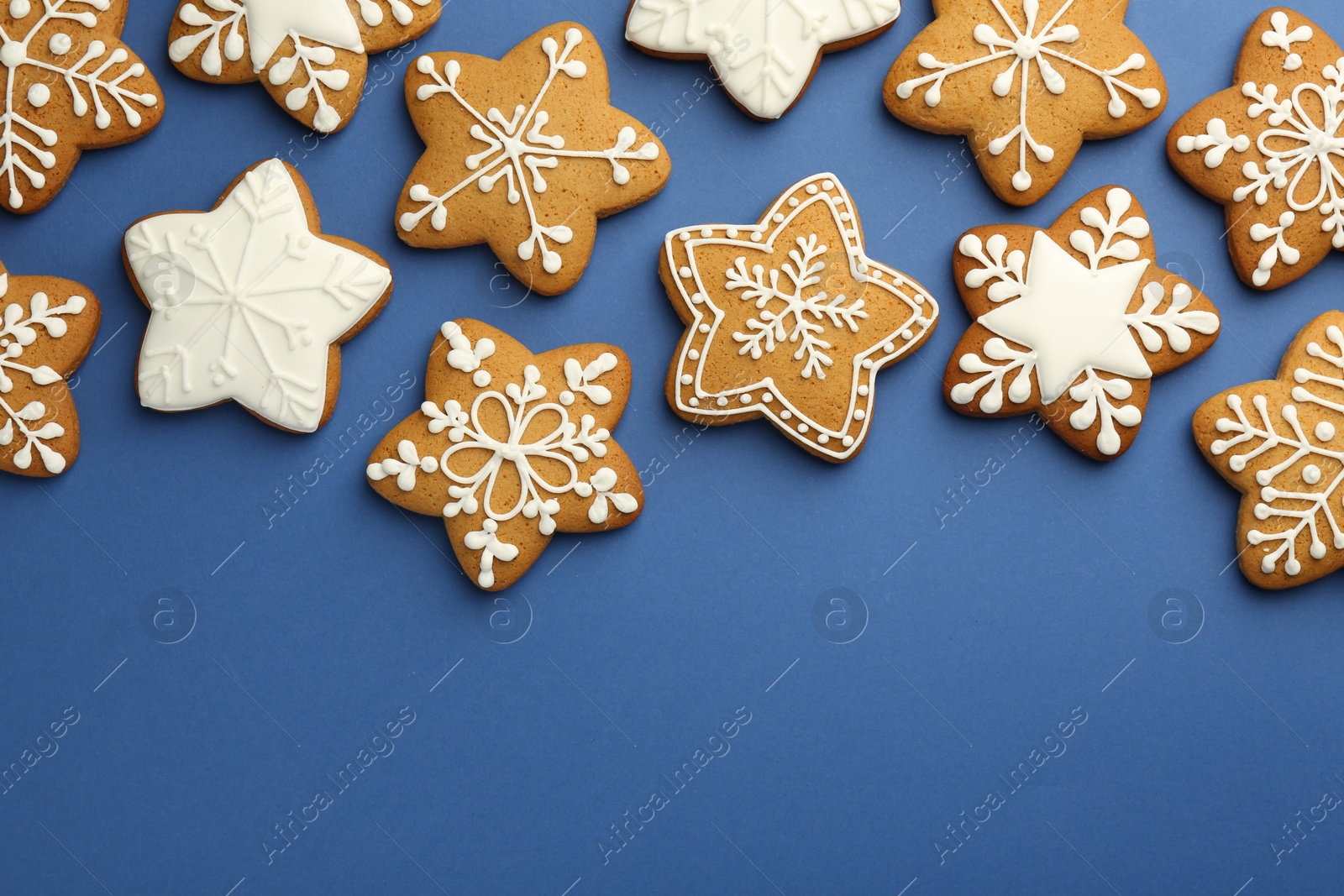 Photo of Tasty star shaped Christmas cookies with icing on blue background, flat lay. Space for text