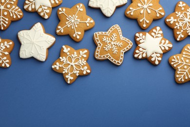 Photo of Tasty star shaped Christmas cookies with icing on blue background, flat lay. Space for text