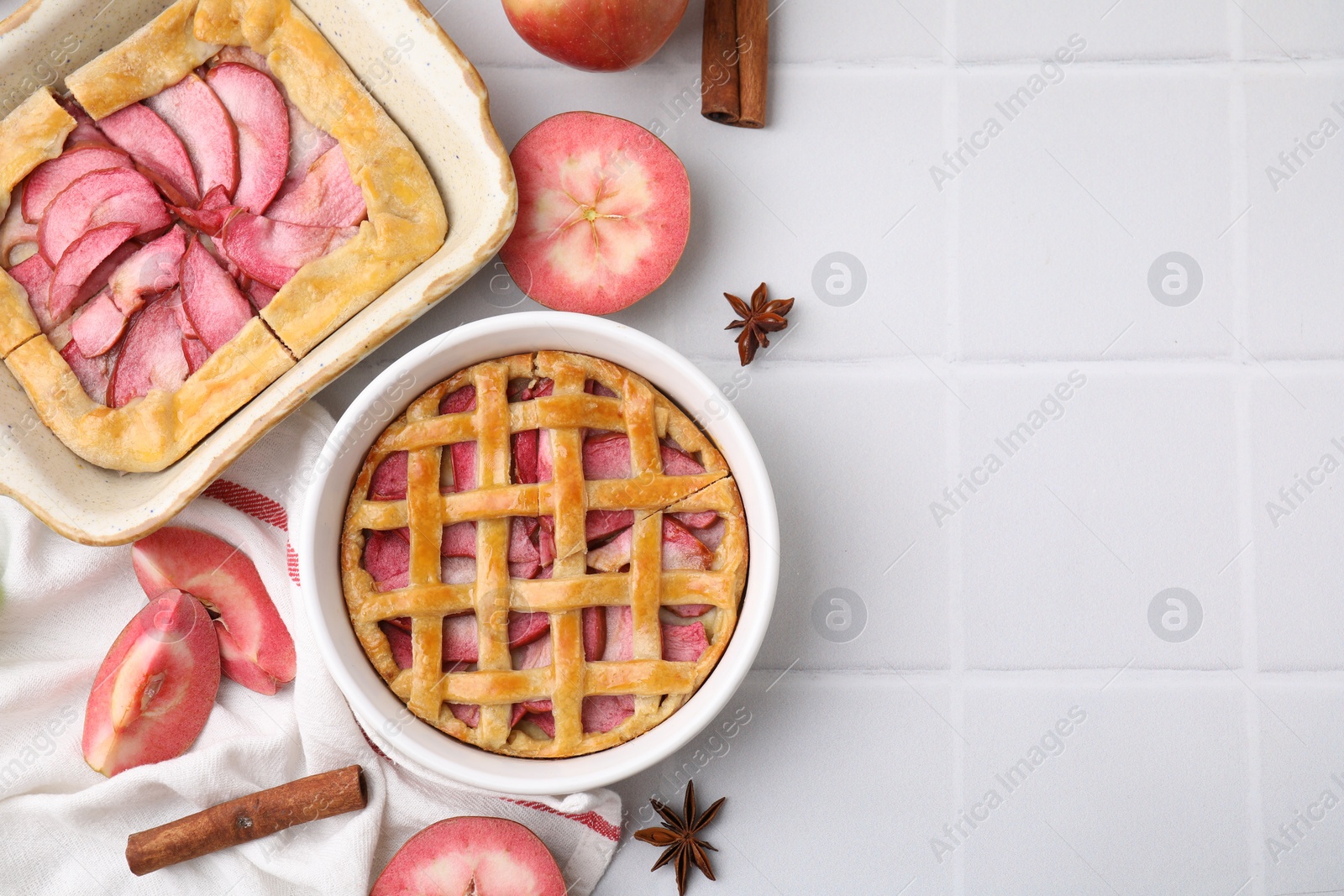Photo of Delicious apple pie, galette and ingredients on white tiled table, flat lay. Space for text
