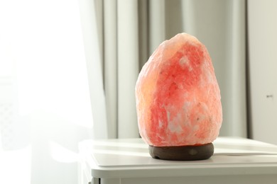 Photo of Himalayan salt lamp on white table indoors, space for text