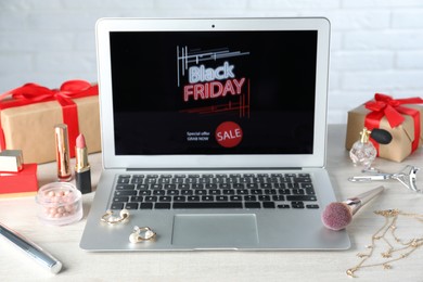 Photo of Laptop, gift boxes and women's accessories on white wooden table. Black Friday sale