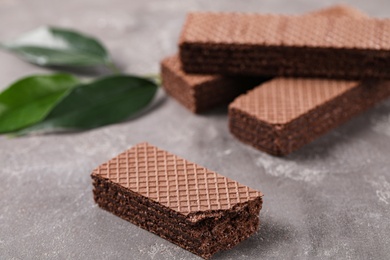 Delicious chocolate wafers with leaves on grey stone background