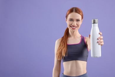 Photo of Woman in sportswear with thermo bottle on violet background, space for text