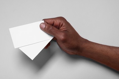 African American man holding paper cards on white background, closeup. Mockup for design