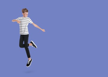 Boy jumping on light blue background, space for text