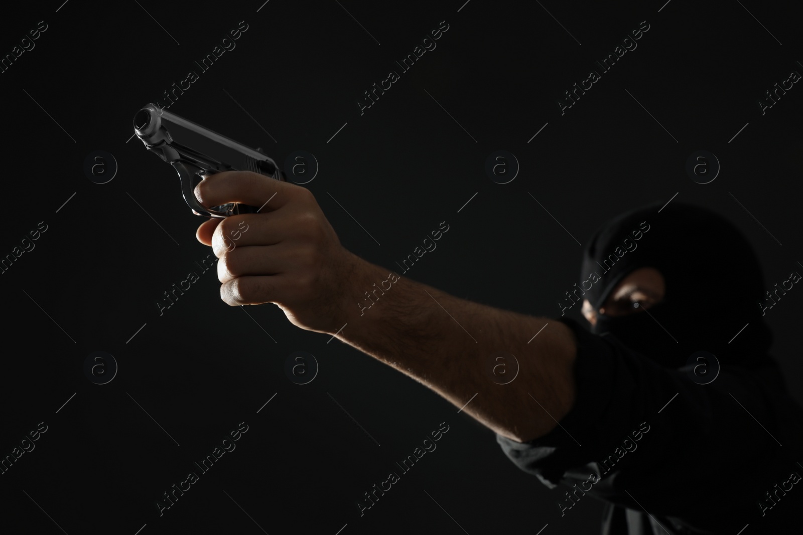 Photo of Professional killer on black background, focus on gun