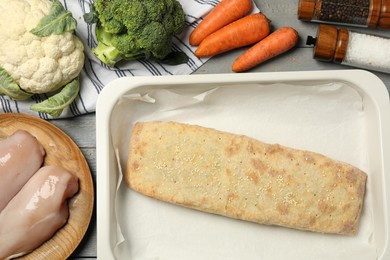Photo of Delicious strudel with chicken and vegetables on grey wooden table, flat lay