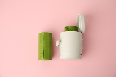 Photo of Dog waste bags and dispenser on pink background, flat lay