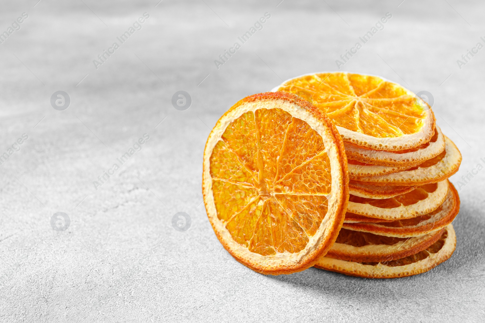 Photo of Dry orange slices on light grey table, space for text