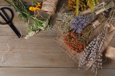 Photo of Different herbs, thread and scissors on wooden table, flat lay. Space for text
