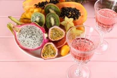 Delicious exotic fruits and wine on pink wooden table