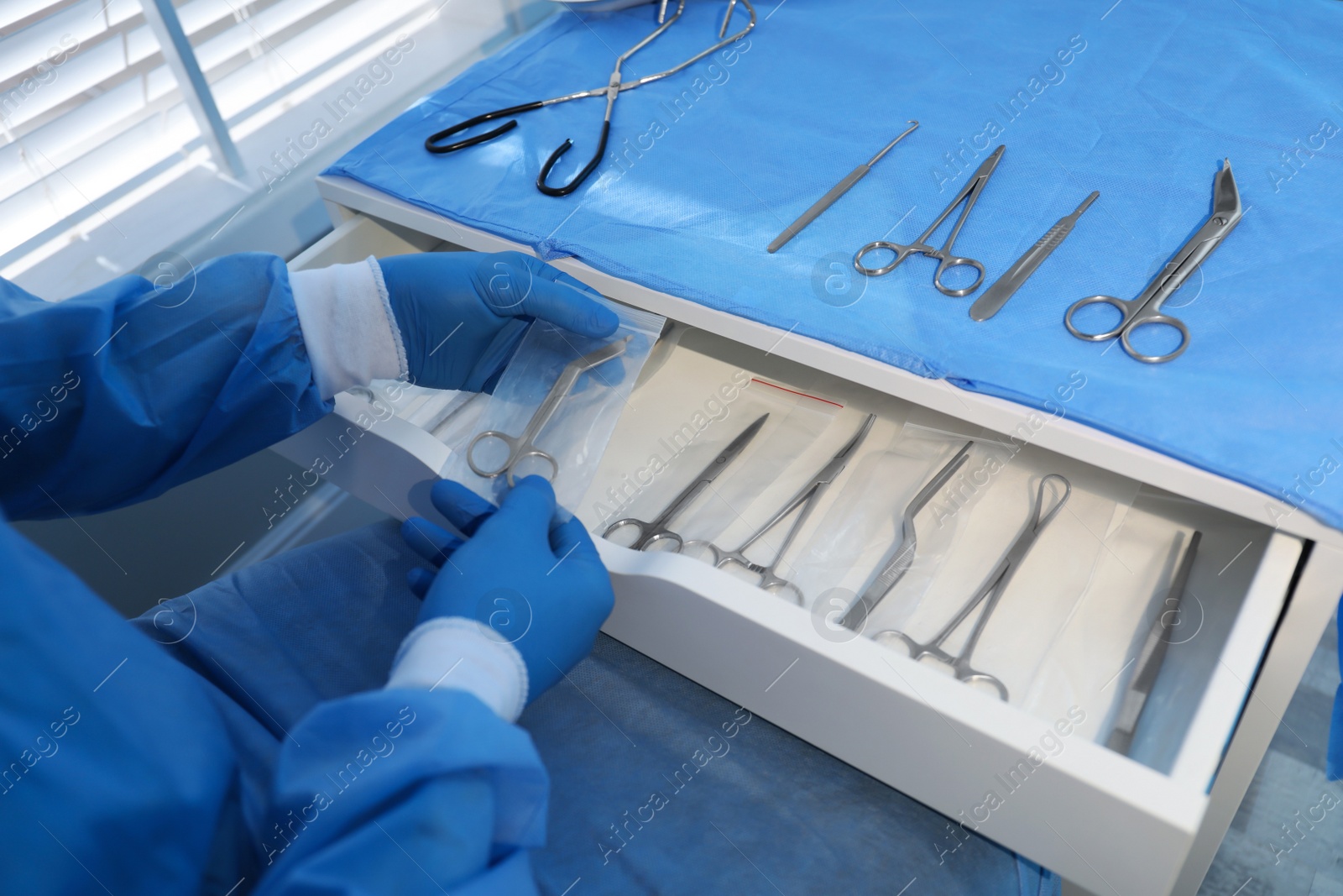 Photo of Doctor putting Pott's scissors into drawer indoors, closeup. Table with different surgical instruments