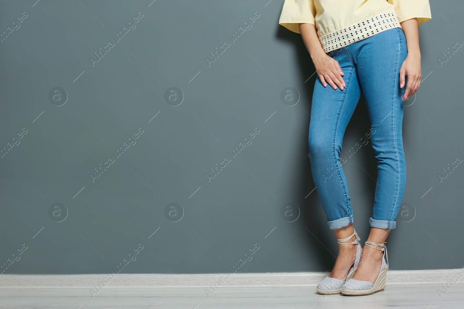 Photo of Young woman with sexy legs near grey wall