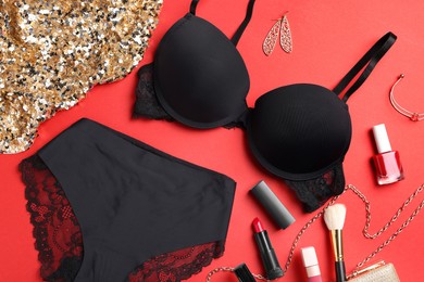 Flat lay composition with black women's underwear and cosmetic products on red background