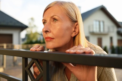 Photo of Concept of private life. Curious senior woman spying on neighbours over fence outdoors