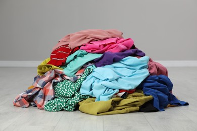 Photo of Pile of dirty clothes on floor near grey wall indoors