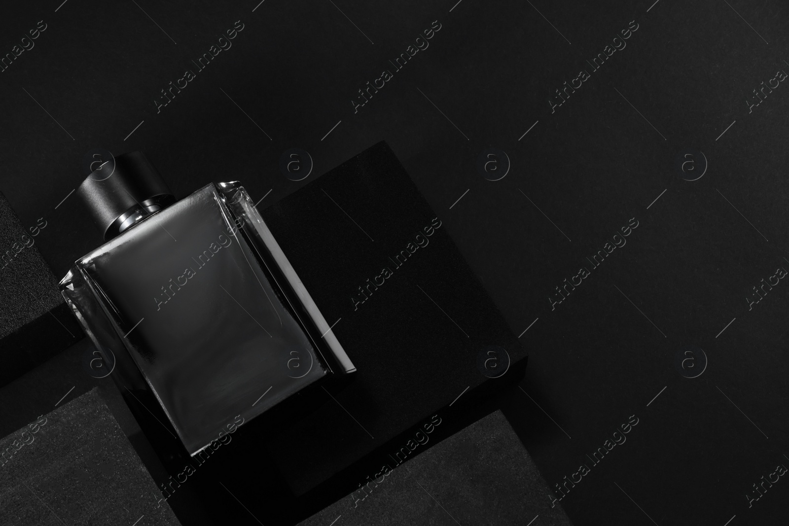 Photo of Stylish presentation of luxury men`s perfume in bottle on black background, top view. space for text